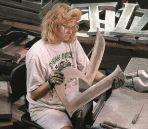Woman hand-finishing metal letter