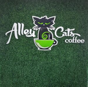 Playful black cat logo for “Alley Cats Coffee” on a green faux plant wall, using Formed plastic in an eye-catching setup.