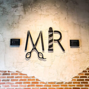 Flat Cut Metal letters for interior salon signage on stone wall. 