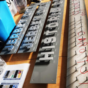 Flat Cut Metal letters assembled on wayfinding signage in busy downtown street. 